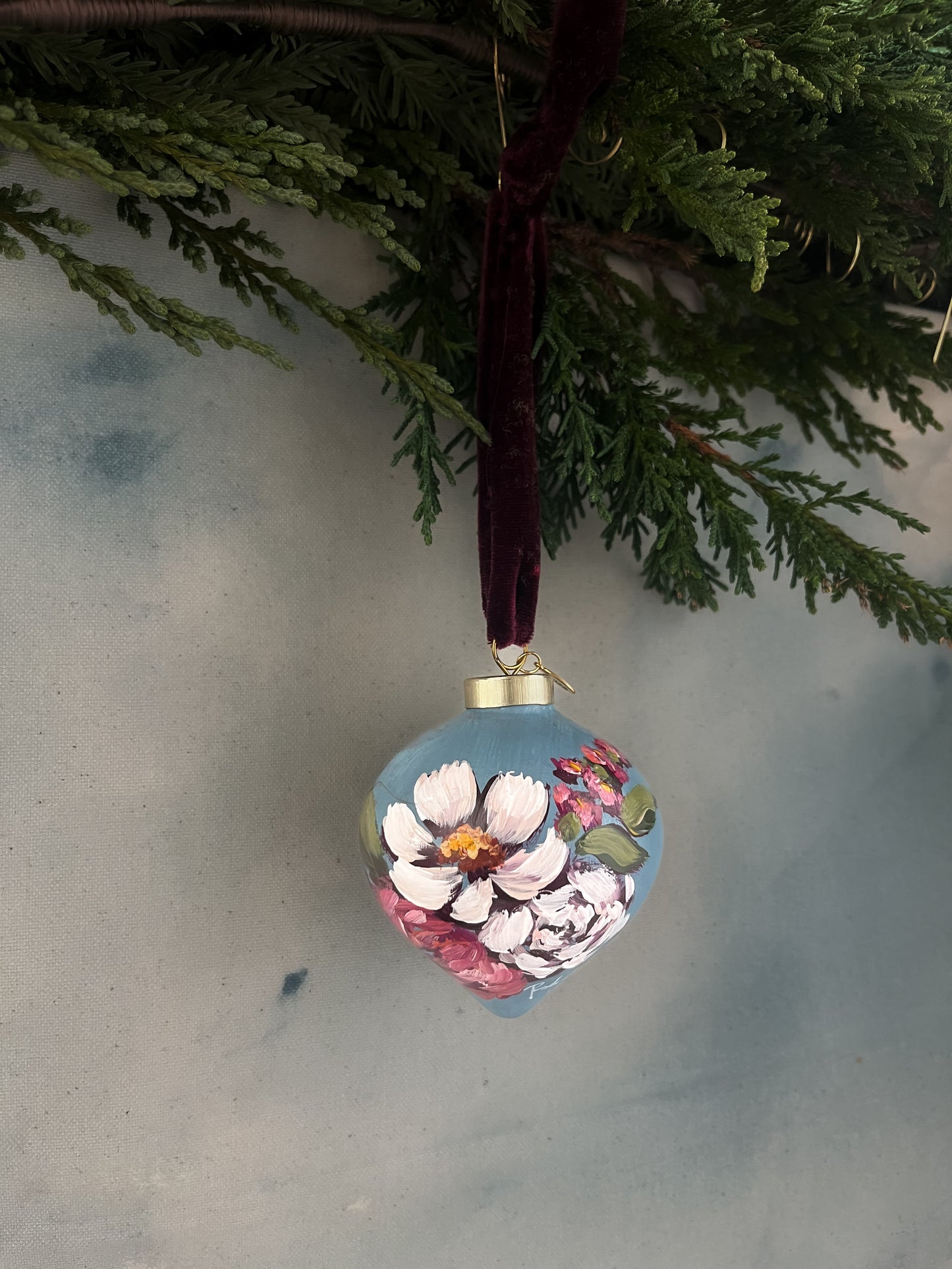 Decorative floral ornament hanging from a branch against a neutral background