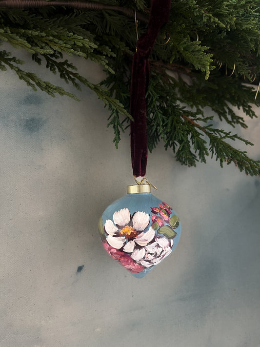 Decorative floral ornament hanging from a branch against a neutral background